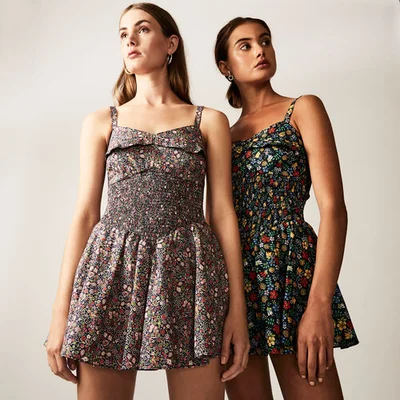 Two female models wearing matching floral print dresses standing against a plain white background in Sydney.