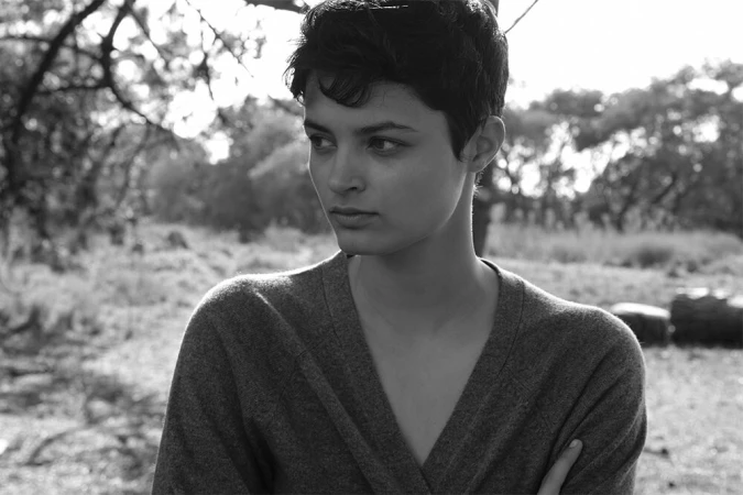 Monochrome portrait of a woman with short dark hair in a V-neck sweater outdoors in Sydney with trees