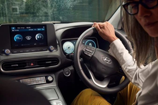 View of the inside of a Hyundai car with an adult woman driver, showcasing the car's modern dashboard and interior features.