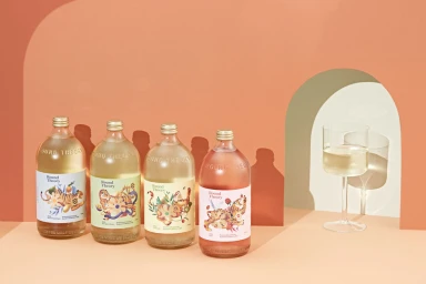 Four glass wine bottles with illustrated labels featuring tigers, arranged in a row with a glass of white wine on a terracotta arched set
