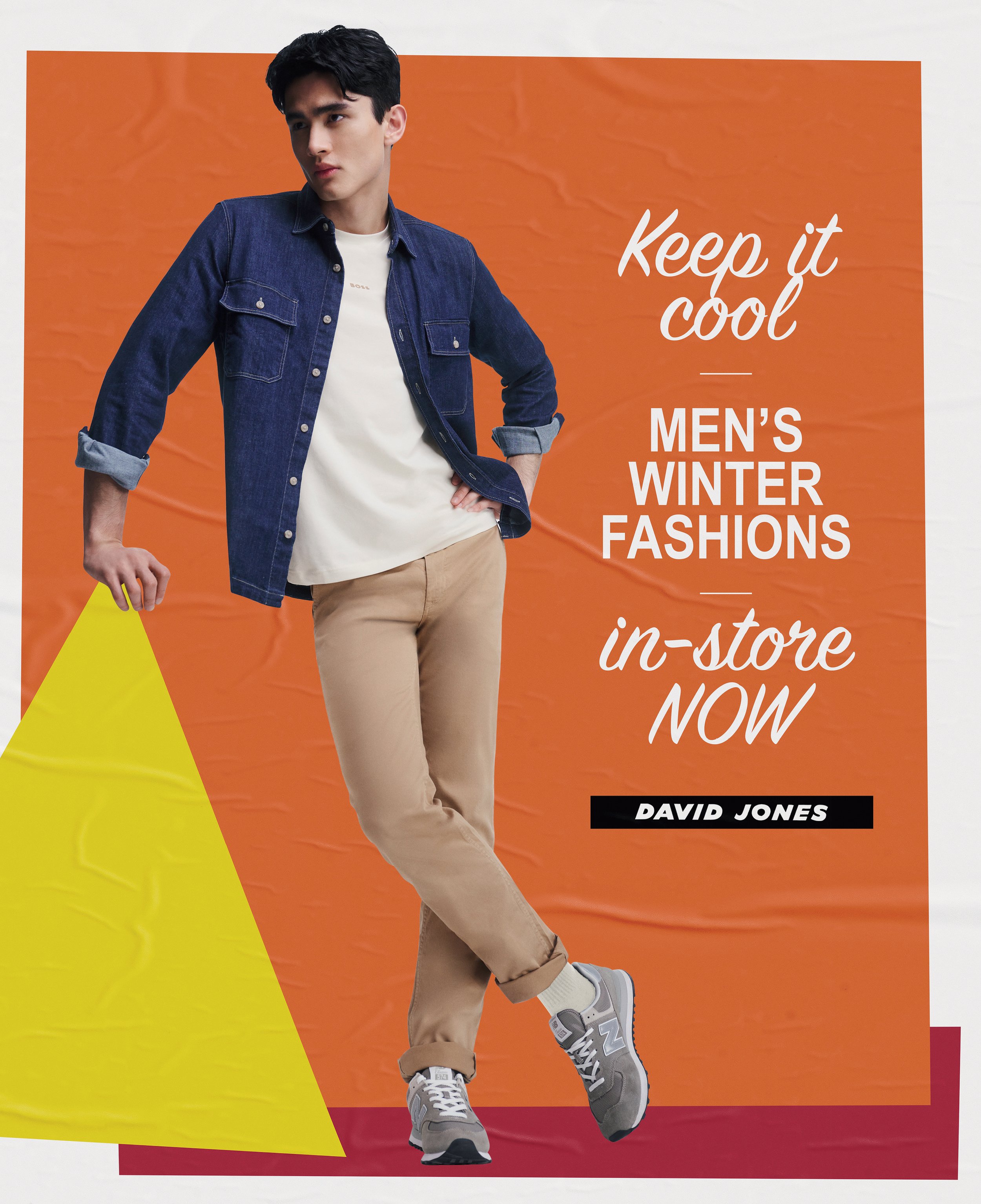 Fashion advertisement features a young adult male in a denim shirt and tan pants posing against an orange background with bold white text.