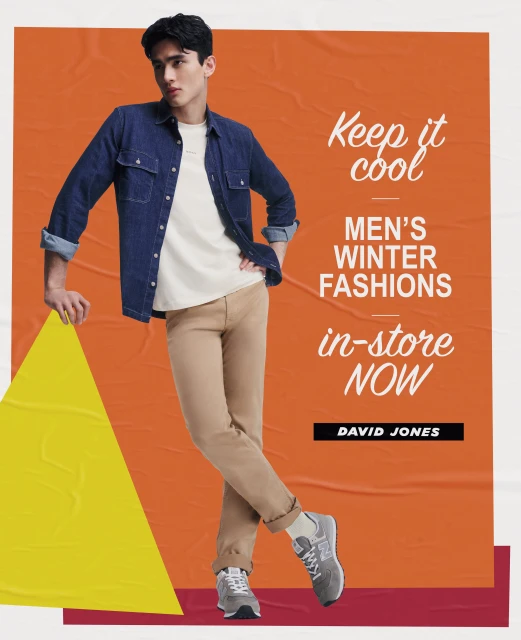 Fashion advertisement features a young adult male in a denim shirt and tan pants posing against an orange background with bold white text.