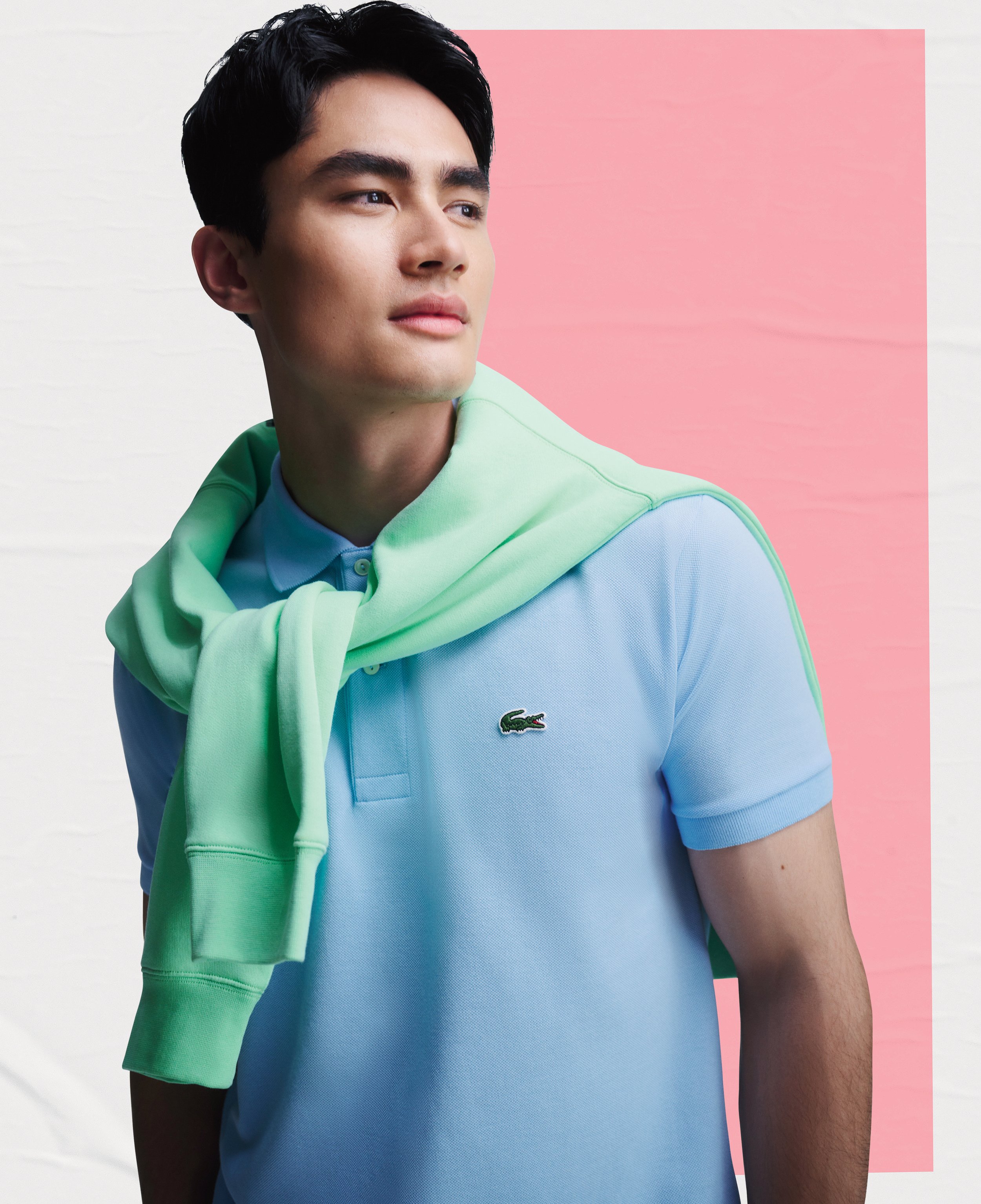 Portrait of an Asian adult male wearing a light blue Lacoste polo shirt, with a light green sweater around his shoulders.