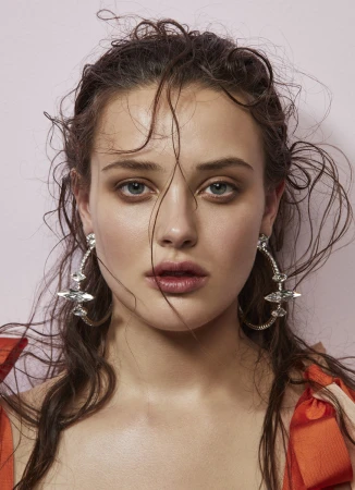Close-up portrait of a woman with wet hair wearing large crystal hoop earrings and an orange top against a pale background