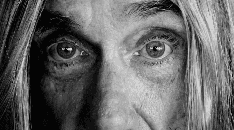 Black-and-white close-up of an adult's face with eyes looking straight ahead, framed by long hair, showcasing facial details and texture.