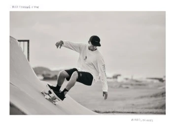 Man wearing a baseball cap and long sleeve shirt skateboarding down a concrete ramp in a black and white photograph by Mike Calvino