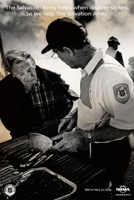 Monochrome image of two adult men, one serving food from a grill, possibly assisting during disaster relief, with Salvation Army text.