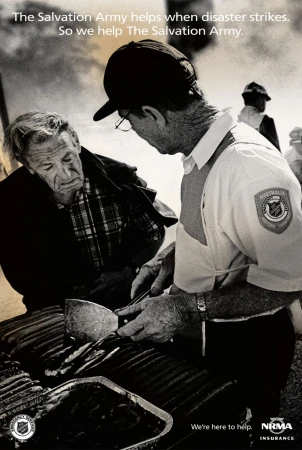Monochrome image of two adult men, one serving food from a grill, possibly assisting during disaster relief, with Salvation Army text.