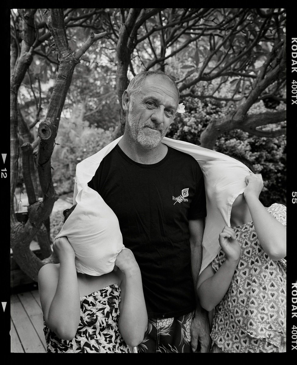 Monochrome shot of a mature man with two children in an outdoor setting, with a sheet draped over their heads.