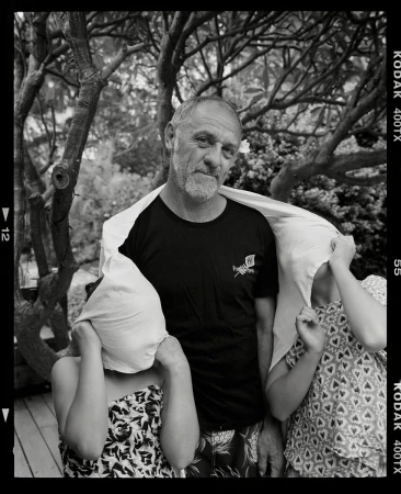 Monochrome shot of a mature man with two children in an outdoor setting, with a sheet draped over their heads.