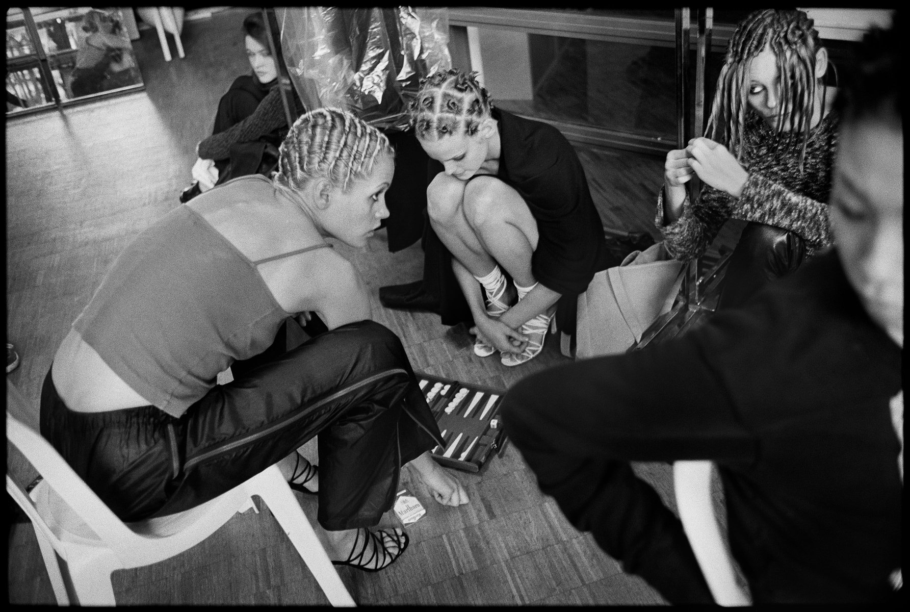 Black and white studio shot captures five adult women with distinct hairstyles, seated indoors, embodying fashion-forward individuality and style.