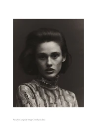 Portrait of a woman with voluminous dark hair wearing a patterned knit top against a dark background