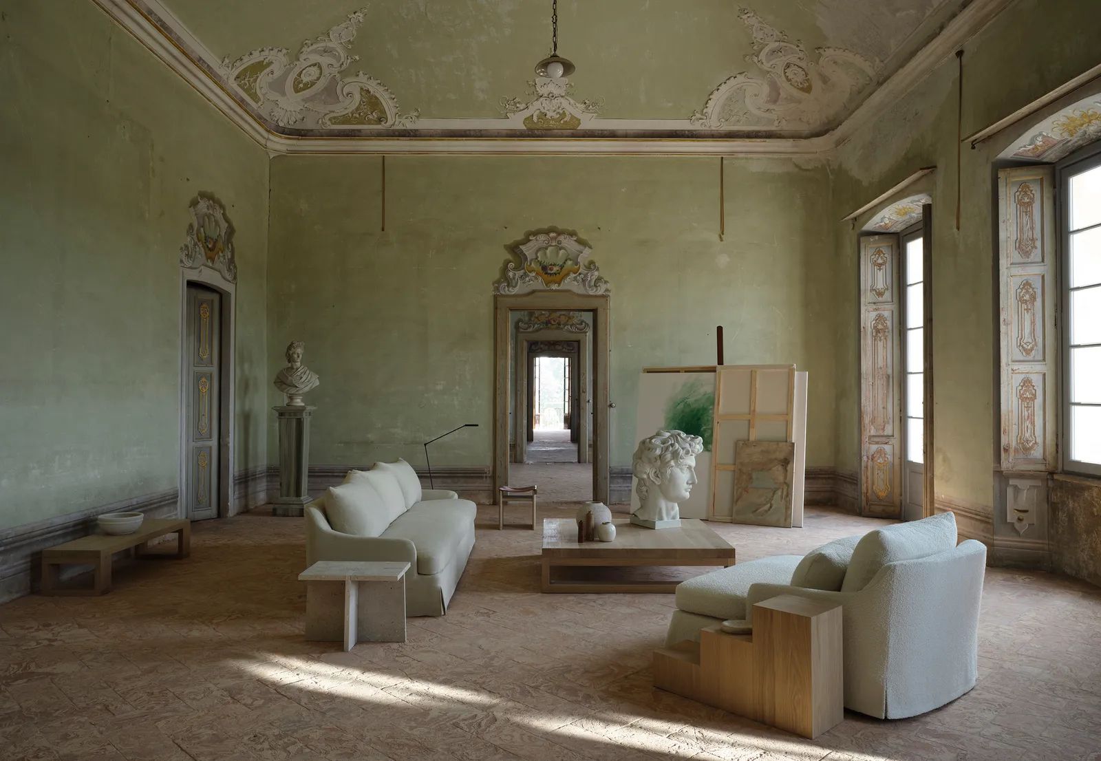 Living room interior showcasing off-white furniture, including sofa and chaise lounge, accented with a sculpture and sunlit ambiance.