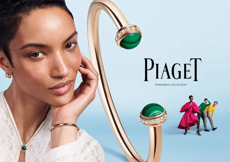 Close-up portrait of a woman wearing a gold malachite pendant necklace next to a Piaget Possession bracelet on a light blue background.