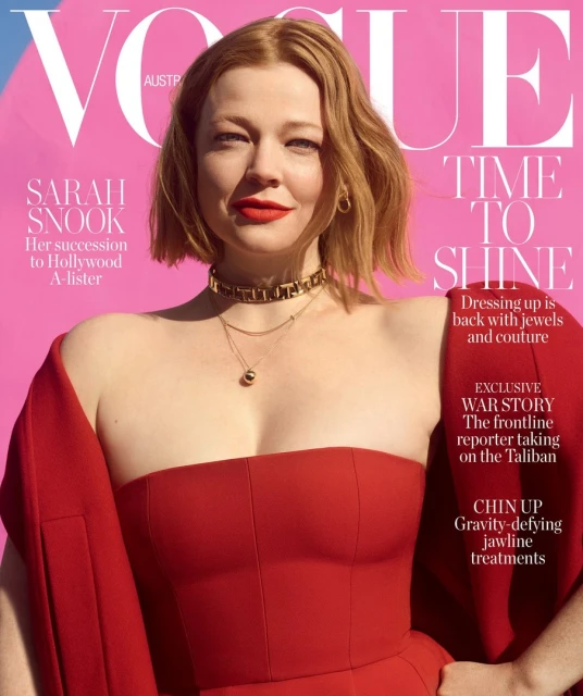 Sarah Snook appears on the cover of Vogue Australia, wearing a red dress and jewelry against a pink background.