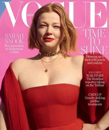 Sarah Snook appears on the cover of Vogue Australia, wearing a red dress and jewelry against a pink background.