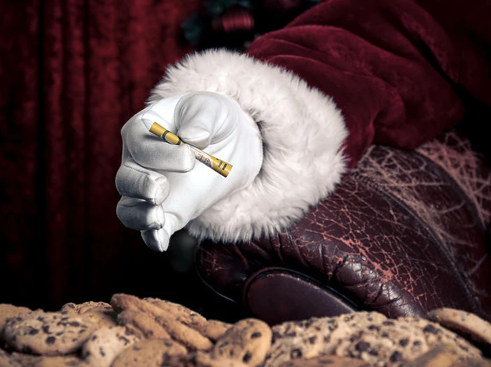Santa Claus offering a treat: a gloved hand holds a sugar-rolled stick next to chocolate chip cookies, set against a red velvet backdrop.