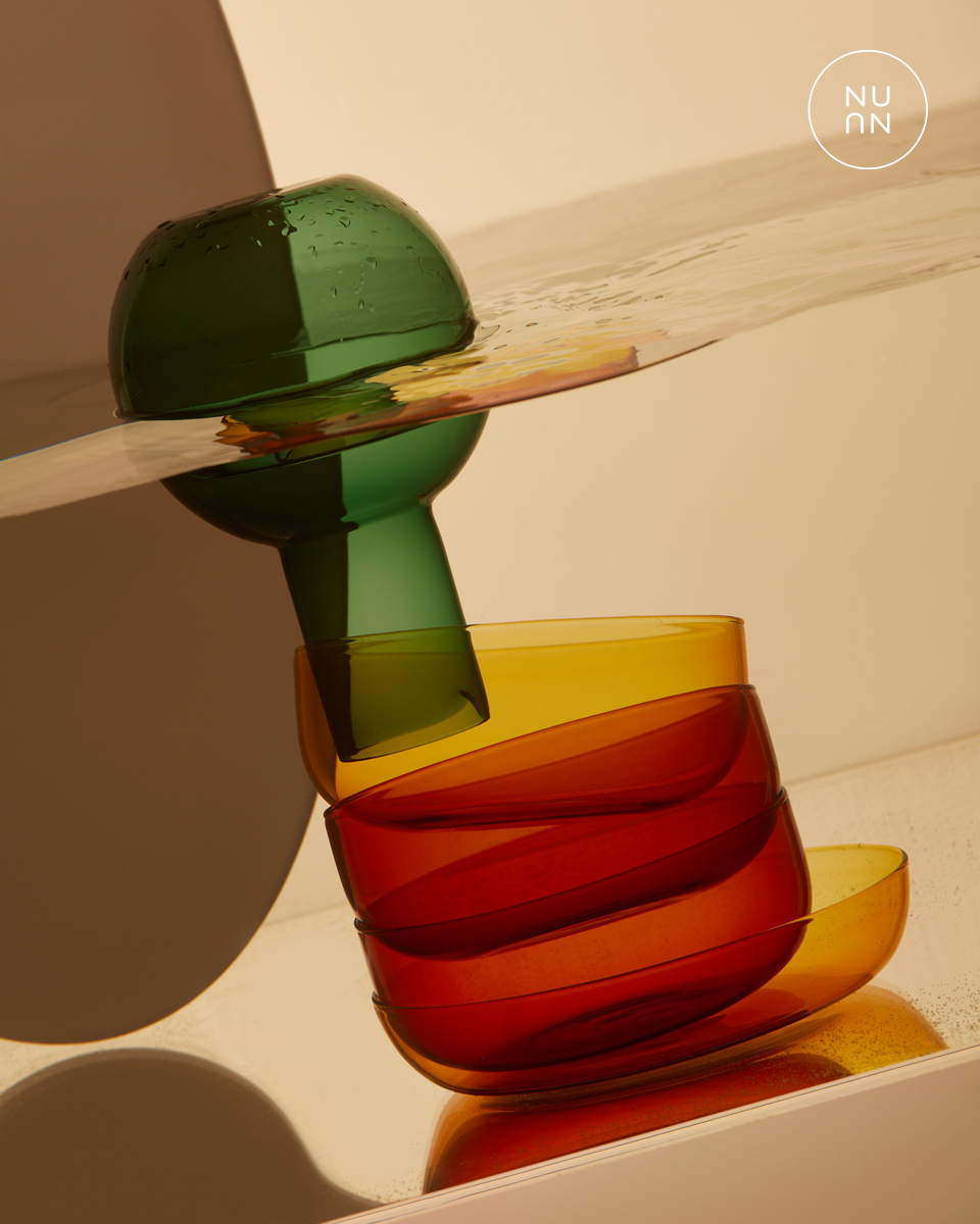 Artistic shot of stacked red and yellow glass bowls with a green glass on top, creating a visually striking and colorful composition.
