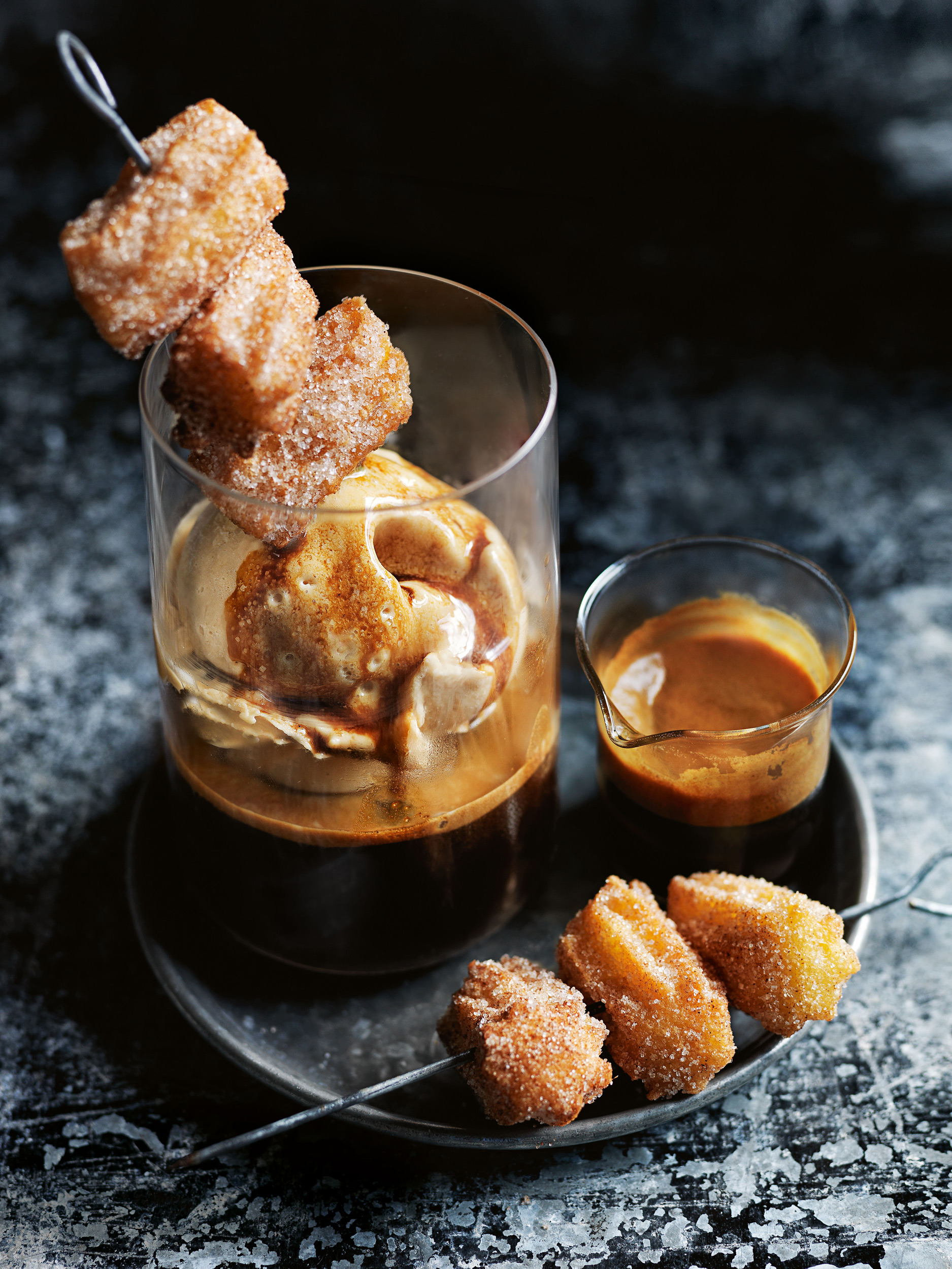Affogato dessert: coffee, ice cream, and churros skewers on a metal plate. Food and beverage photography.