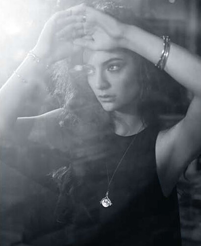 Monochrome portrait of a woman with her hands raised to her forehead wearing bracelets and a pendant necklace