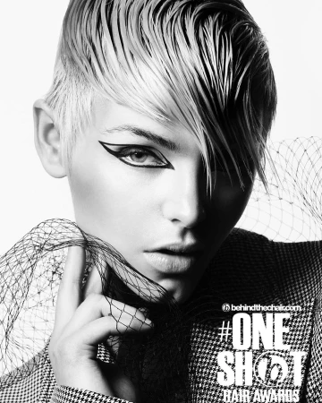 Close-up monochrome portrait of a model with short textured wet-look hair and bold graphic eyeliner styling.