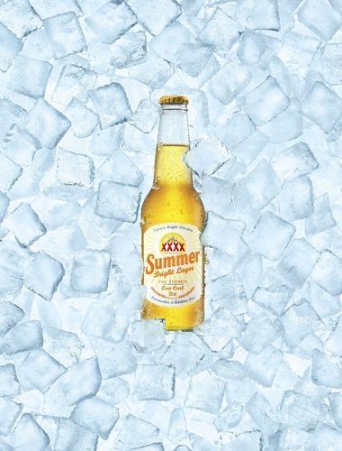 A bottle of XXXX Summer Bright Lager beer is positioned amidst a bed of ice cubes, suggesting a refreshing and cold beverage.
