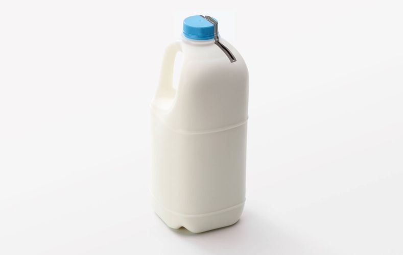 Milk jug with a blue cap on a white background in a studio setting. The jug is plastic and rectangular.