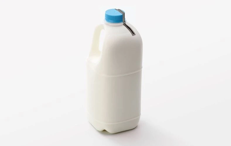 Milk jug with a blue cap on a white background in a studio setting. The jug is plastic and rectangular.
