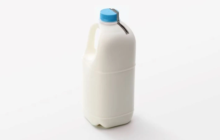 Milk jug with a blue cap on a white background in a studio setting. The jug is plastic and rectangular.