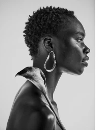 Black woman in profile wearing a large silver hoop earring and holding a Calla lily, styled by Vanessa Collins.