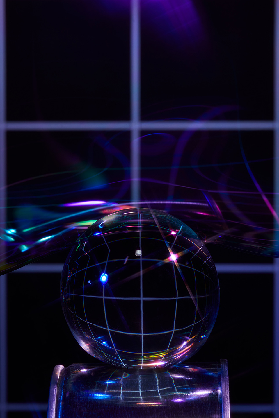 Abstract photograph of a crystal ball with a grid pattern, resting on a metallic cylinder against a dark background with neon light effects.