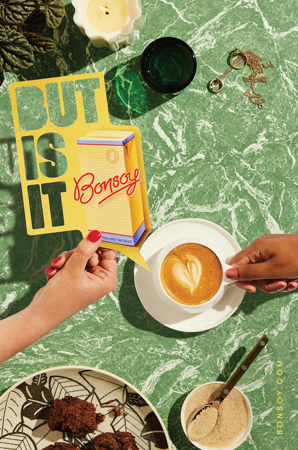 Overhead shot of two hands, one holding a Bonsoy package cutout, the other holding a coffee cup, with cookies and breakfast items.