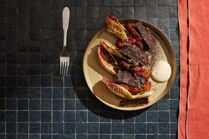Overhead food photography of roasted vegetables with radicchio and a dollop of cream on a plate styled by Jess Johnson