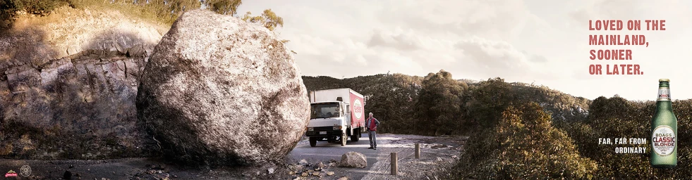 Giant boulder blocking a rural road with a delivery truck and a man standing nearby in an expansive landscape