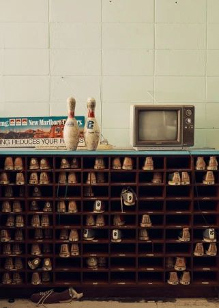 Vintage bowling alley details: Bowling pins, old television, and shoe cubbies create a nostalgic retro scene with muted color palette.