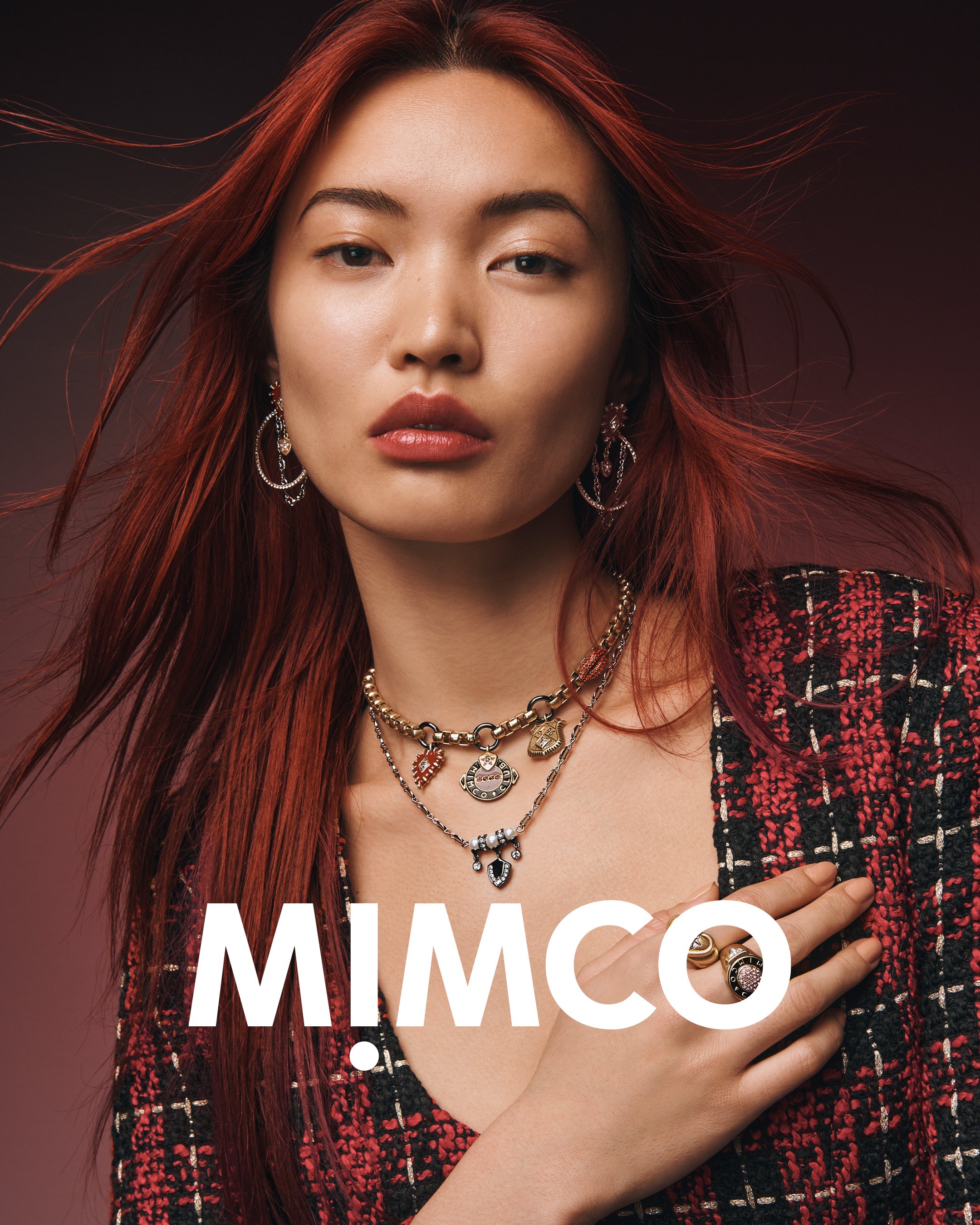 Close-up portrait of an Asian female model with red hair wearing gold jewelry, a colorful necklace, and a black and red jacket.