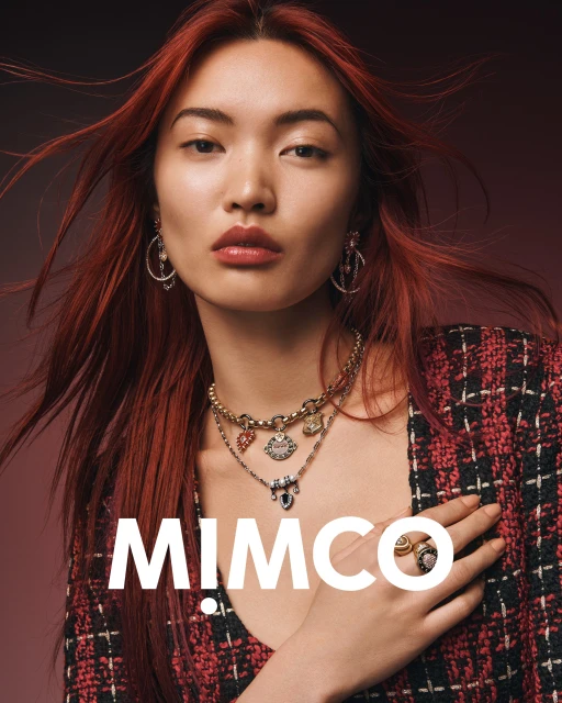 Close-up portrait of an Asian female model with red hair wearing gold jewelry, a colorful necklace, and a black and red jacket.