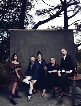 Group of five people posed in front of an outdoor grey backdrop with trees framing the scene in Sydney.