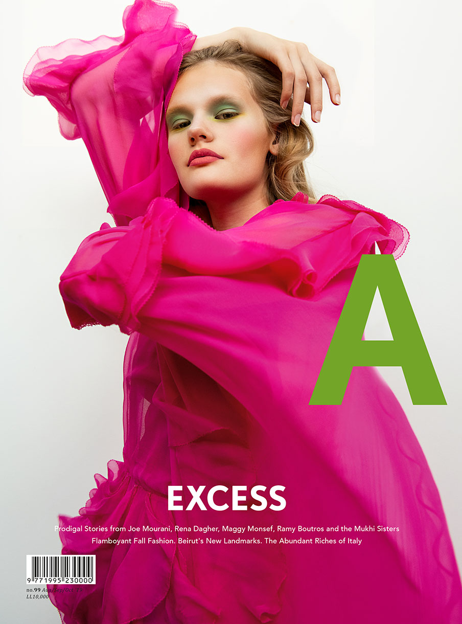 Fashion magazine cover with a model in a pink dress and green eye shadow posing in front of a white and green background.
