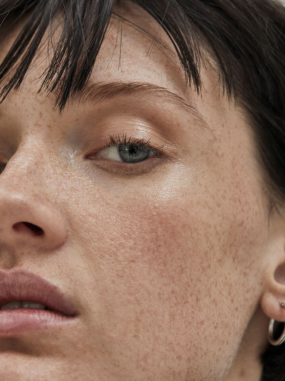 Close-up beauty portrait of a woman with freckles, short dark fringe, and natural makeup by Charlotte Niketic in Sydney