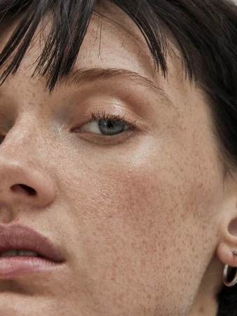 Close-up beauty portrait of a woman with freckles, short dark fringe, and natural makeup by Charlotte Niketic in Sydney