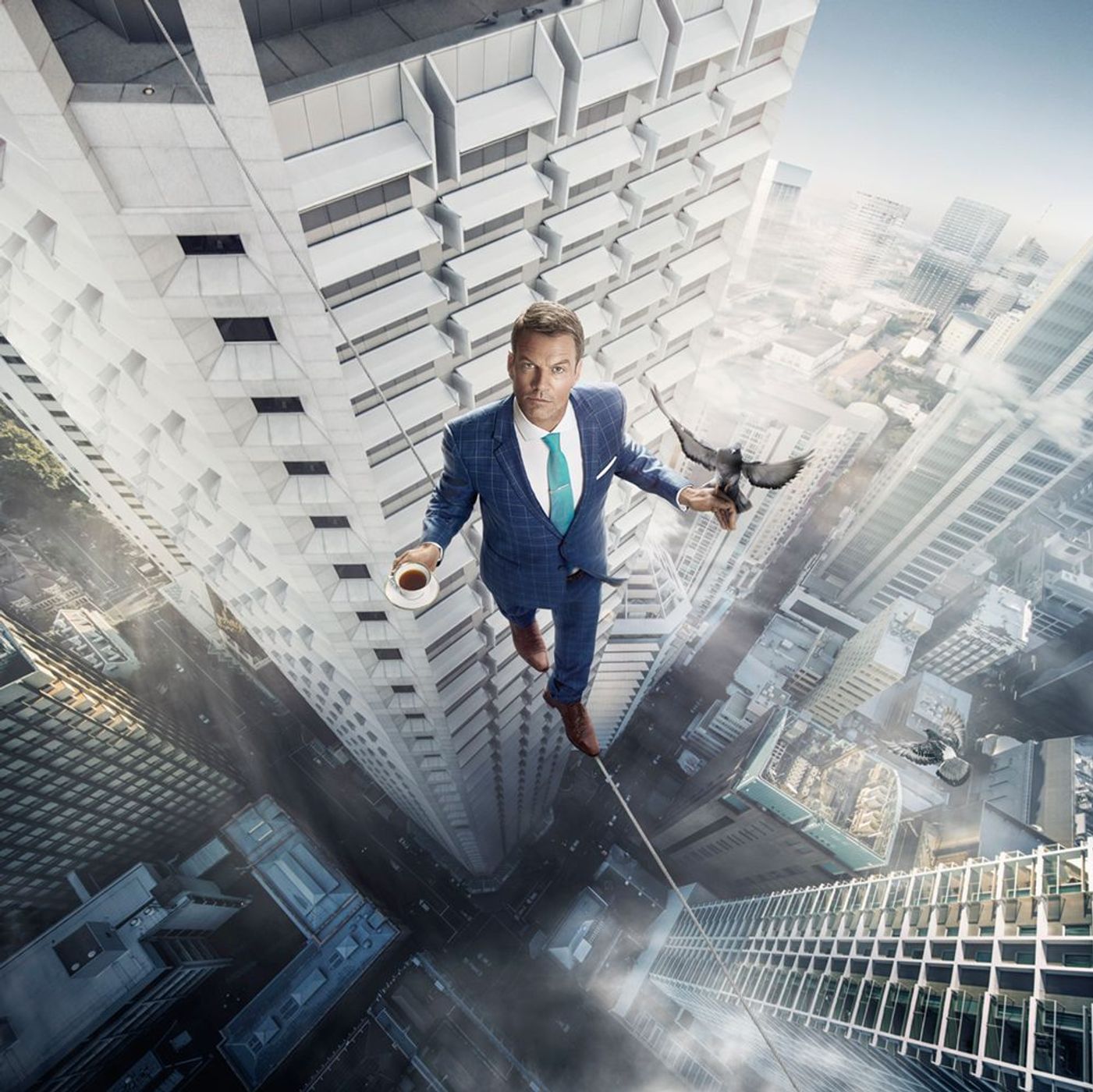 Adult male in a blue suit walks a tightrope between skyscrapers with a bird on his hand and a coffee cup in the city.