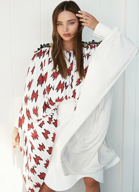 A woman in a white dress with red lightning bolt patterns on the bodice and a white sleeve with white background, beauty shot.