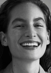 Close-up monochrome portrait of a smiling woman with freckles and wet-look hair by photographer Sylve Colless.