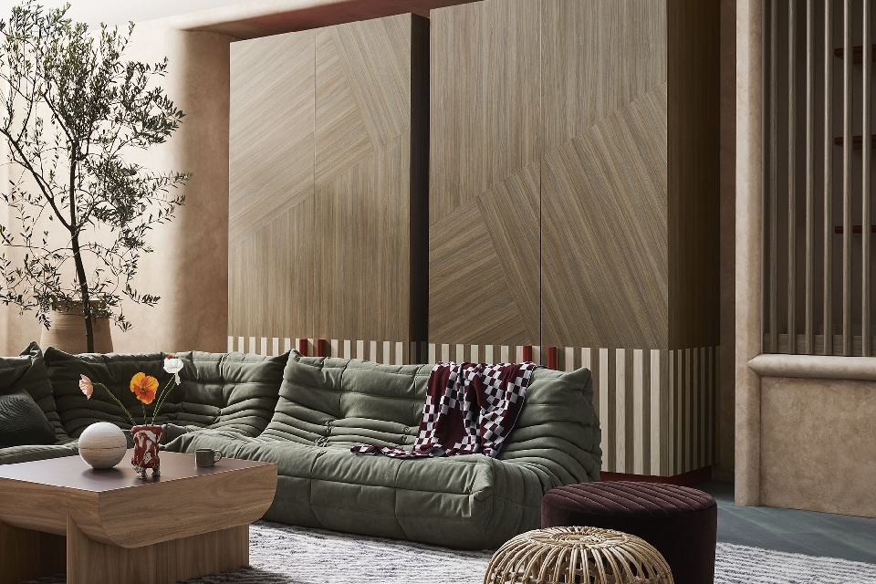 Living room interior showcasing a modular green sofa, a wooden coffee table with floral arrangement, and a decorative tree near a cabinet.