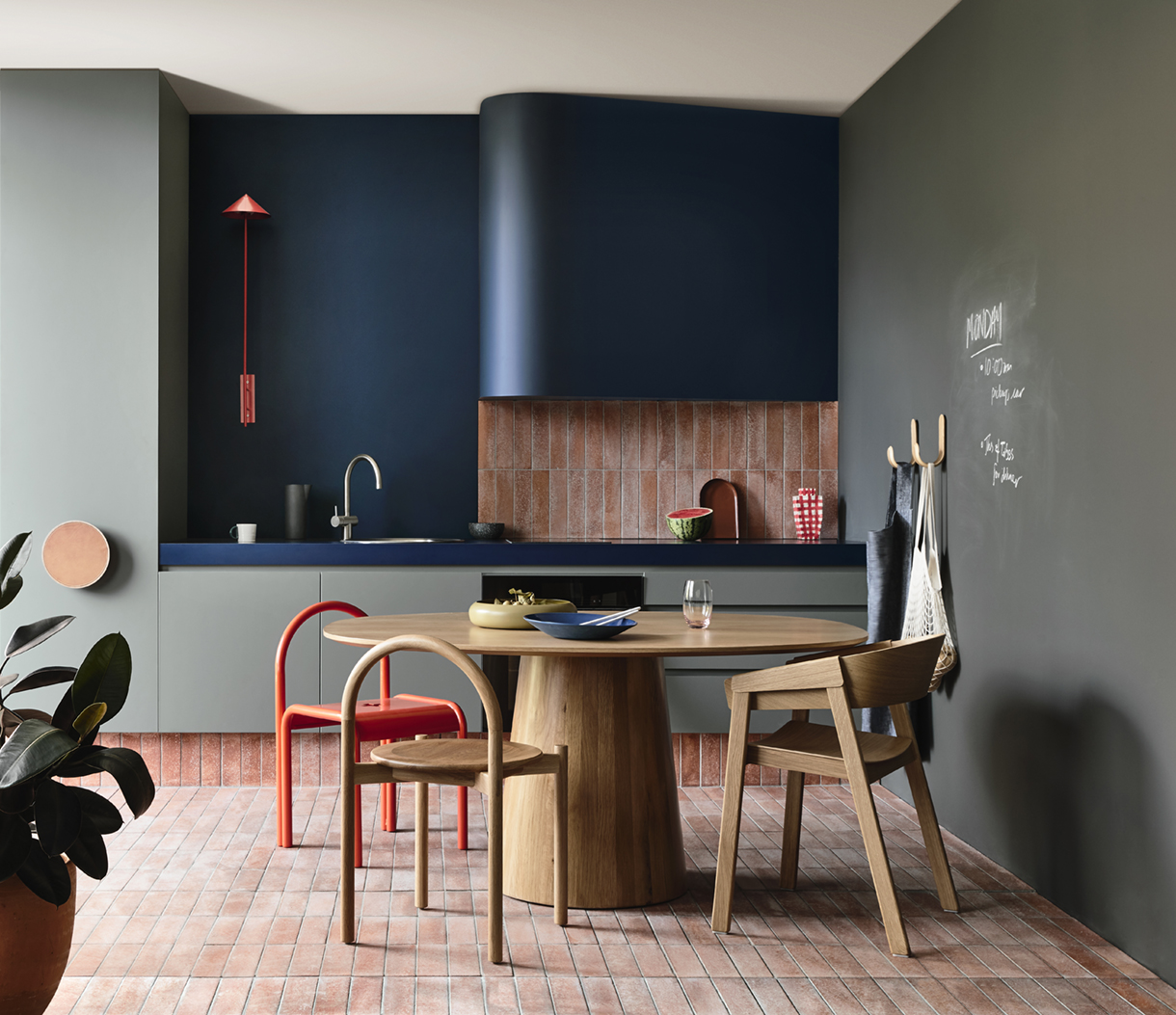 Stylish kitchen interior featuring a round wooden table, colorful chairs, modern cabinetry, and muted wall colors in a residential setting.