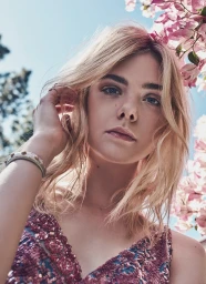 Portrait of blonde woman posing among pink flowers under a bright blue sky, photographed by Beau Grealy.