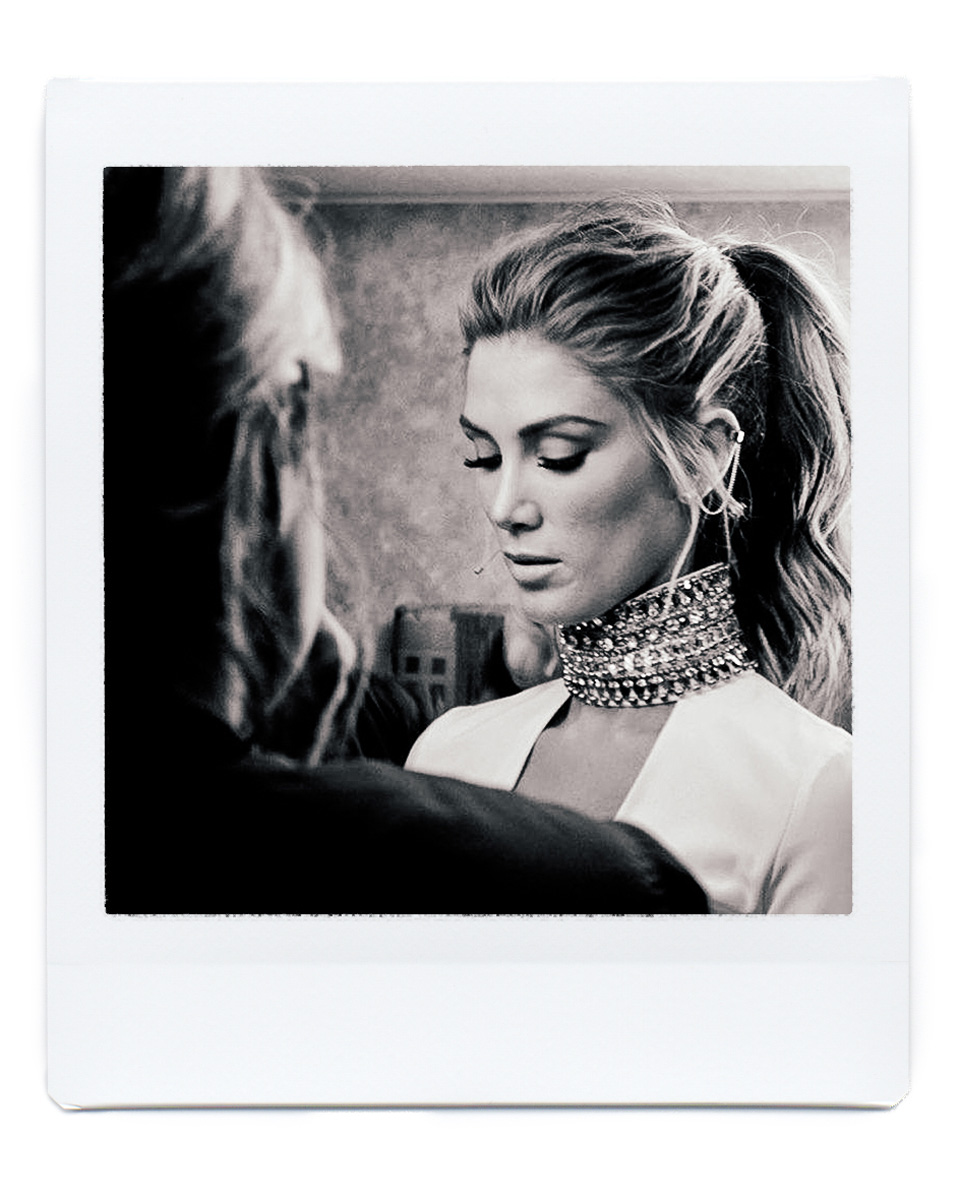 Monochrome portrait of a woman with a high ponytail and an elaborate beaded choker necklace; photographed in a photo studio with soft lighting.