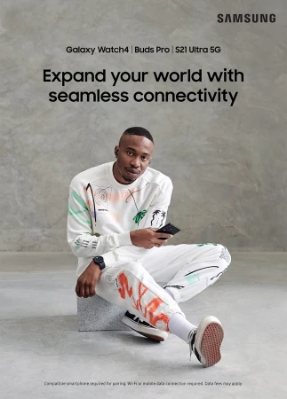 Samsung ad featuring an adult male wearing ear buds, a smartwatch, and holding a smartphone while sitting against a gray background.