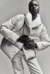 Black model wearing an oversized white puffer jacket and white trousers against a neutral background